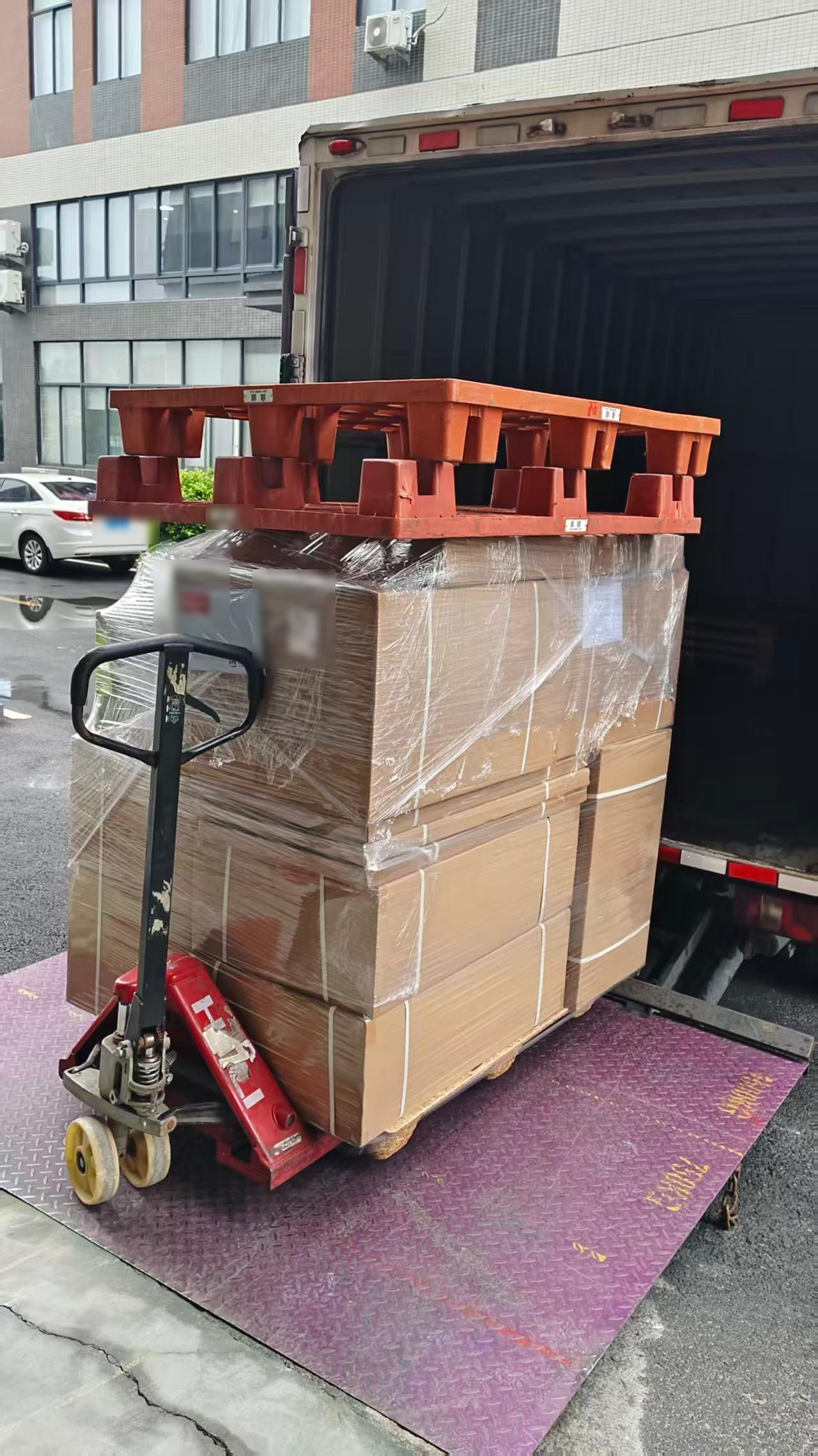 Shrink-wrapped pallet of chamber cartons being loaded onto a lorry for inland transport to the departure port