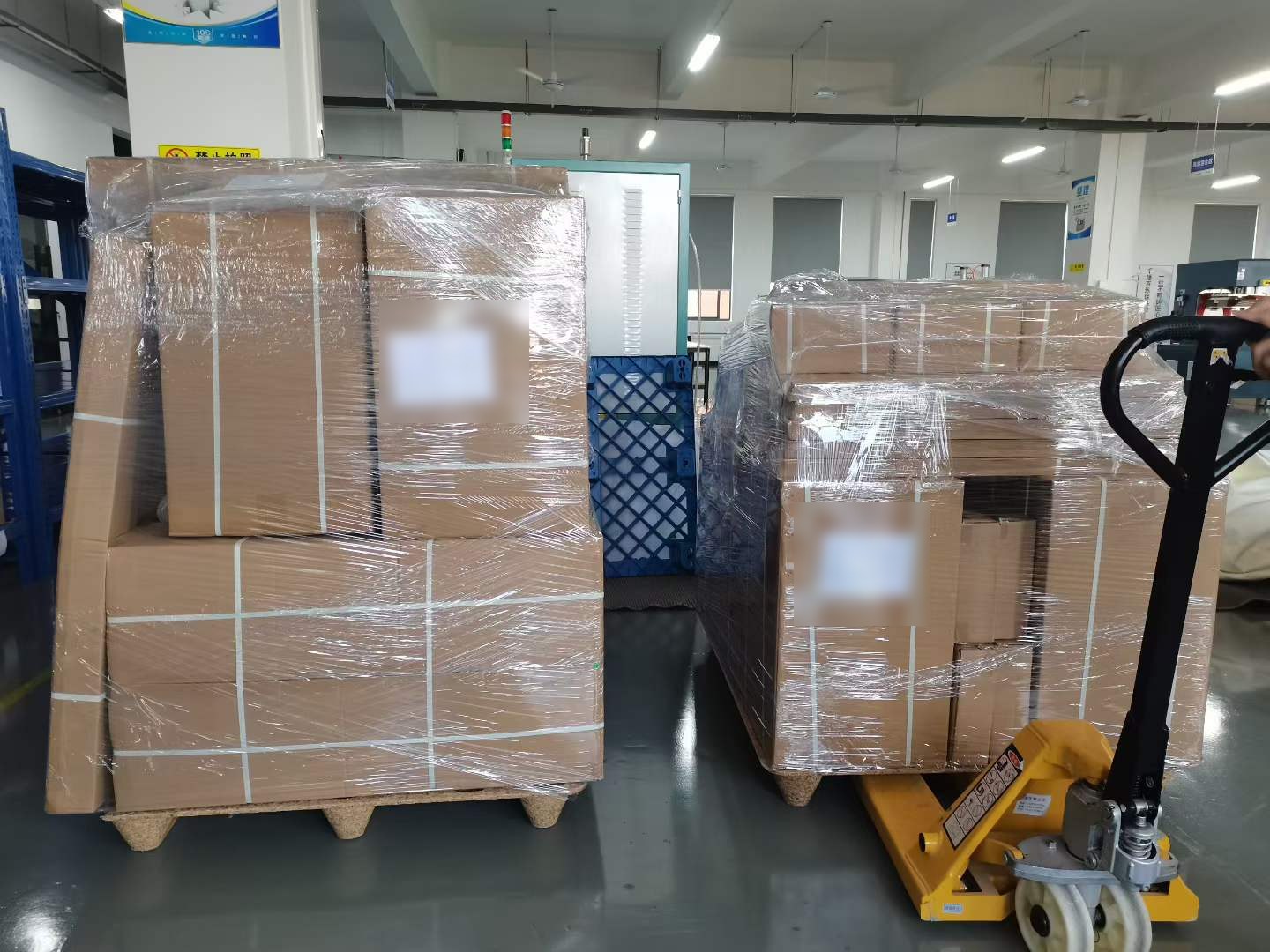 Two pallets of plain brown cartons, shrink-wrapped and strapped, staged in the factory